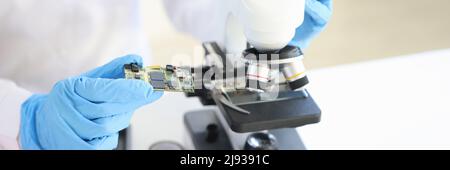 Scientist looking under microscope computer processor closeup Stock Photo
