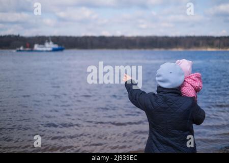 Grandmother walking with her granddaughter outside near river showing a ship Stock Photo