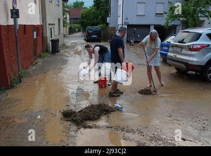 Oberstenfeld, Germany. 19th May, 2022. Residents sweep mud and flotsam from the street after a violent thunderstorm with hail and heavy rain that fell over the town in the evening hours. Some streets were covered with mud, several cellars were flooded. Credit: Hemmann/SDMG/dpa/Alamy Live News Stock Photo