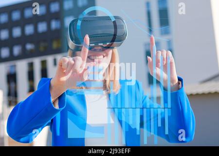 Young woman using virtual reality goggles to analyze data and graphics in colorful neon lights. Futuristic future concept in business.  Stock Photo
