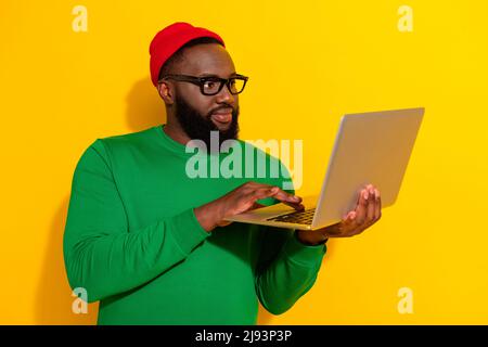 Portrait of attractive focused skilled guy using laptop typing finance project isolated over bright yellow color background Stock Photo