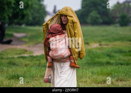 London UK, 20 May 2022. A woman with a toddler  braves  the rain showers on Wimbledon Common, south west London on a rainy overcast morning as the warm weather spell comes to an end . The Met office  has issued weather warning  that a 'blood rain' could hit the UK as a result of a Saharan dust cloud mixing with rain .Credit. amer ghazzal/Alamy Live News Stock Photo