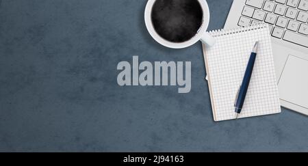 top down view of laptop computer, coffee cup and notepad with pen on dark desk with copy space Stock Photo