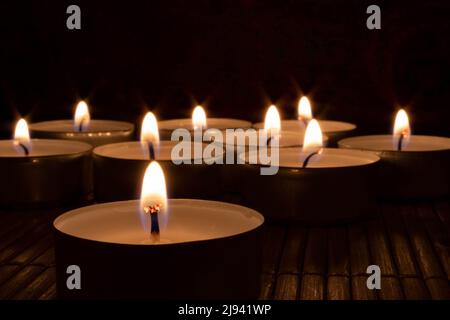 Lit tealight candles in dark setting Stock Photo