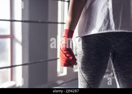 Midsection of caucasian young female boxer wearing red boxing wrap clenching fist in boxing ring Stock Photo