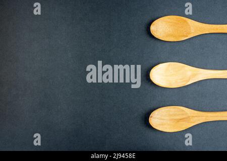 Wooden spoons small made of light brown wood on dark background with copy space and top view Stock Photo