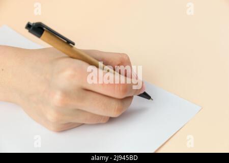 Closeup of woman's hand writing on paper, selective focus. Stock Photo