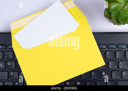 Office letter, card, invitation mock up template with blank empty white paper, yellow envelope and keyboard top view Stock Photo