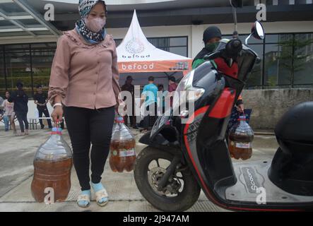 Jakarta, Indonesia. 20th May, 2022. A woman carrying two tanks of cooking oil walks out of a market in Jakarta, Indonesia, May 20, 2022. Indonesia will lift an export ban on crude palm oil, cooking oil, refined, bleached and deodorized (RBD) palm oil, and RBD palm olein starting May 23, as the country has brought domestic cooking oil prices and supply under control. Credit: Zulkarnain/Xinhua/Alamy Live News Stock Photo