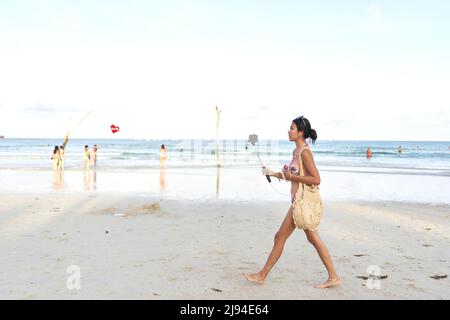 Streamer walking on a beach while doing a live stream using a mobile Stock Photo