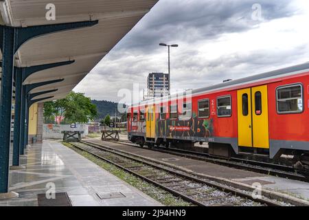 Ljubljana, Slovenia - 07.16.2021: Grafitted train wagon stands near the empty platform of Ljubljana station at the rainy day Stock Photo