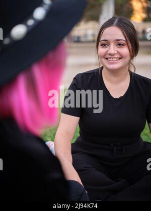 woman sitting smiling and looking at her friend Stock Photo