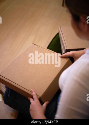 working woman sitting down opening her new product to show it off, view from above Stock Photo