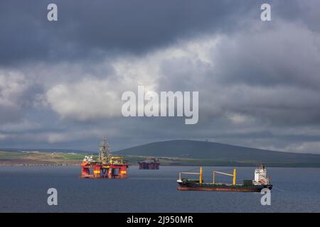 A bulk carrier and oil rigs in Scapa Flow, Orkney Isles, Scotland, UK Stock Photo