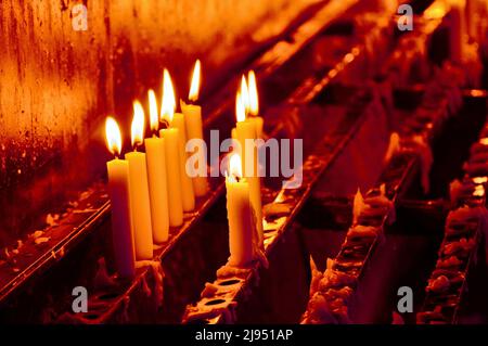 Melting wax on lighted candles reflected on a marble surface in an