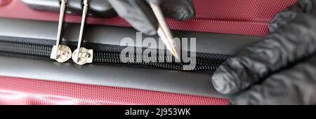 Gloved hands mending a snake on a suitcase Stock Photo
