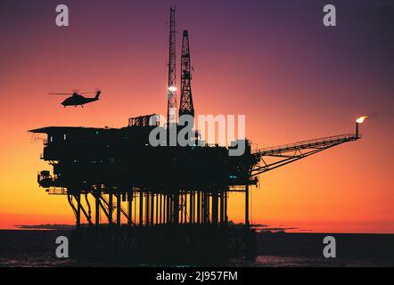 Australia. Industry. Bass Strait. Helicopter landing on Southern Cross oil rig at sunset. Stock Photo