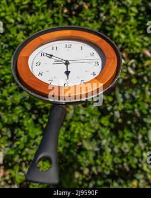 A wall clock is in a pan, against a green background Stock Photo