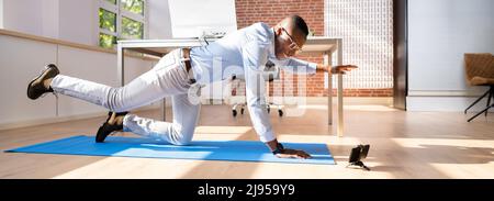 Businessman Doing Stretching Workout Using Smartphone App In Office Stock Photo