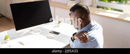 Businessman Suffering From Shoulder Pain While Working In Office Stock Photo