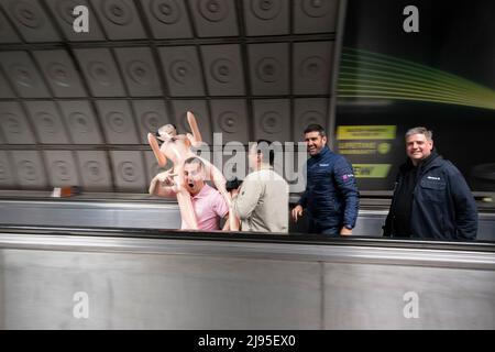 Group of men most likely on a stag party or stag do, travel along the moving walkway at Waterloo station carring a male blow up doll on 30th April 2022 in London, United Kingdom. A bachelor party, also known as a stag weekend, stag do or stag party, or a bucks night is a party held/arranged by the man who is shortly to enter marriage. Stock Photo