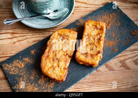 snack with French toast made with bread, milk, eggs and cinnamon, on a wooden table and game for coffee Stock Photo