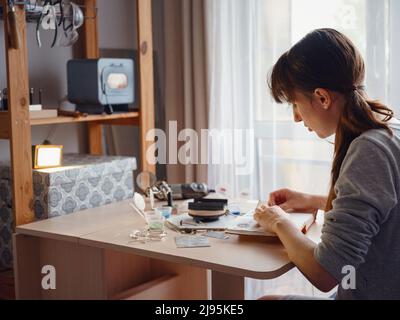 Lifestyle concept, work from home to reinvent your life - Jewelry designer workplace. Woman make jewelry. Georgian minankari enamel manufacturing tech Stock Photo