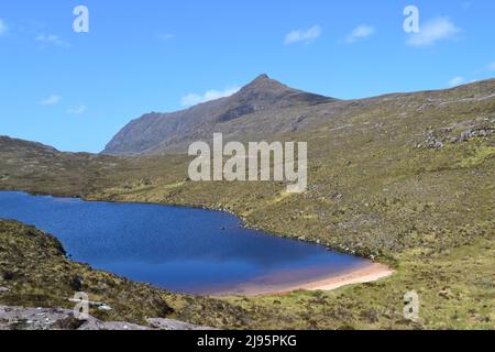 A lachlan with beach below Ben Mor Coigach a high ridge north of Ullapool in Ross & Cromarty/Assynt with far off views of landscapes to the southwest Stock Photo