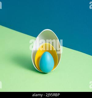 White and yellow eggshells and the whole blue egg on blue and green background. Minimal Easter holiday concept. Creative copy space. Isometric layout Stock Photo