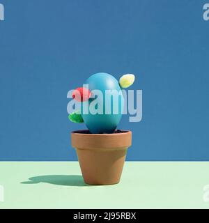 Blue Easter egg arranged like a potted cactus on a green and blue background. Minimal abstract concept. Isometric layout. Square with copy space Stock Photo