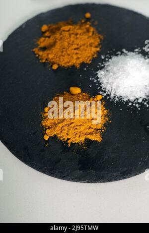 Turmeric, Salt, and Curry spices on a slate chopping board Stock Photo