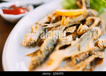 Dish with Mullet Fish With orange. Fried fry small fishes Stock Photo