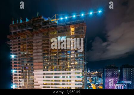 Construction Crane Is Involved In Development Of A New Multi-storey Residential Building. New Residential Multi-storey Houses On Blue Sky. Real Estate Stock Photo