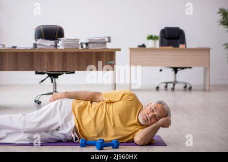 Old boss doing sport exercises during break Stock Photo
