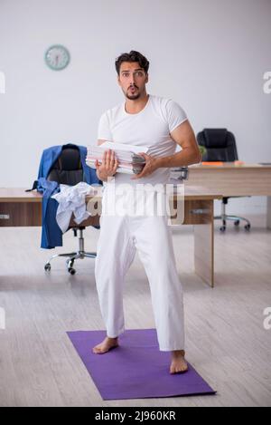 Young businessman employee doing sport exercises at workplace Stock Photo