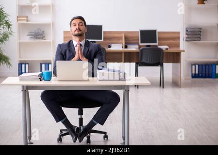 Young businessman employee doing yoga exercises during break Stock Photo