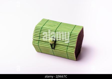 Green toy, closed wicker chest, container on a soft pink background. Chest for secrets, treasure, games with children. Stock Photo
