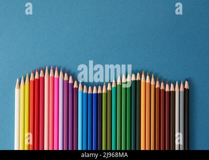 Seamless horizontal pattern Colored pencils arranged in a wave with copy space for note, text, on blue background. Stock Photo