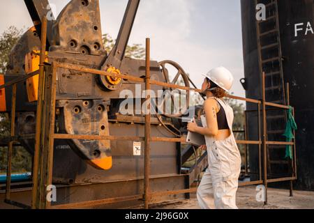 Petrochemical engineering asian woman with  safety helmet standing in oil refinery structure petrochemical industry. Stock Photo