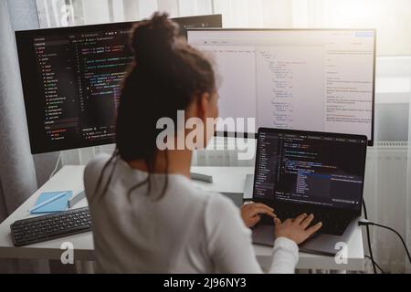 Back view of woman coding on computer, professional female programmer working in room Stock Photo