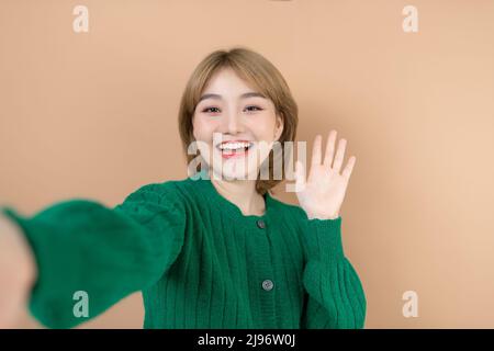 Photo of beautiful lady hold telephone hand making funny selfies online blog translation video call wear casual pink sweater green trousers isolated b Stock Photo