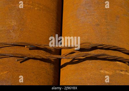 Close-up of two rusty round steel bars bound with wire looking like a piece of industrial art Stock Photo