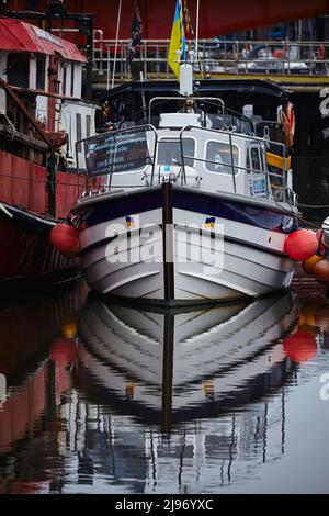 Moored pleasure boat with Ukrainian flag and water reflections. Whitby 16052022 Stock Photo