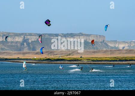 Portland, Dorset, UK.  20th May 2022.  UK Weather:  Kite surfers making the most of the strong breeze at Portland harbour in Dorset on a warm sunny evening.  Picture Credit: Graham Hunt/Alamy Live News Stock Photo