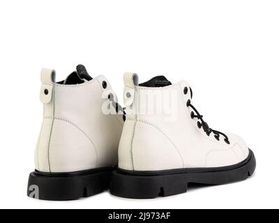 White leather ankle boots with black laces and black rubber sole. Isolated close-up on white background. Back side view. Casual seasonal shoes. Fashio Stock Photo