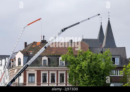 Lippstadt, Germany. 21st May, 2022. Workers repair the damaged roof of a residential building. One day after the tornado, cleanup work has begun in the city center. Credit: David Inderlied/dpa/Alamy Live News Stock Photo