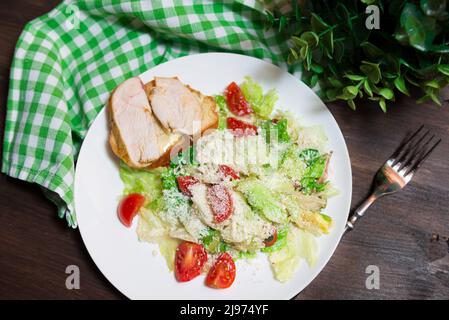 A plate of Caesar salad view from above. Iceberg lettuce, cherry tomatoes, parmesan cheese, chicken fillet. Stock Photo