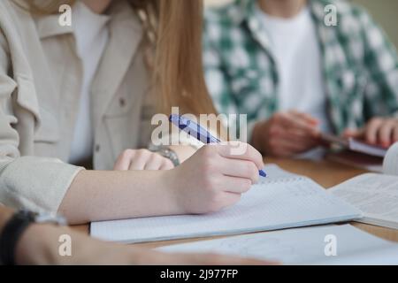 Cropped shot of unrecognizable female student holding a pen, writing notes during class Stock Photo