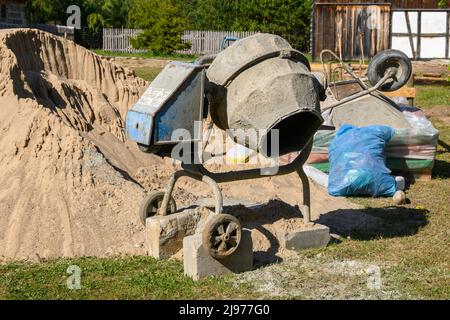 Concrete mixer. Construction site cement mixer machine, tools and sand Stock Photo