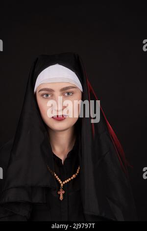 Vertical shot portrait of caucasian nun with wooden cross. Isolated on black background. Stock Photo